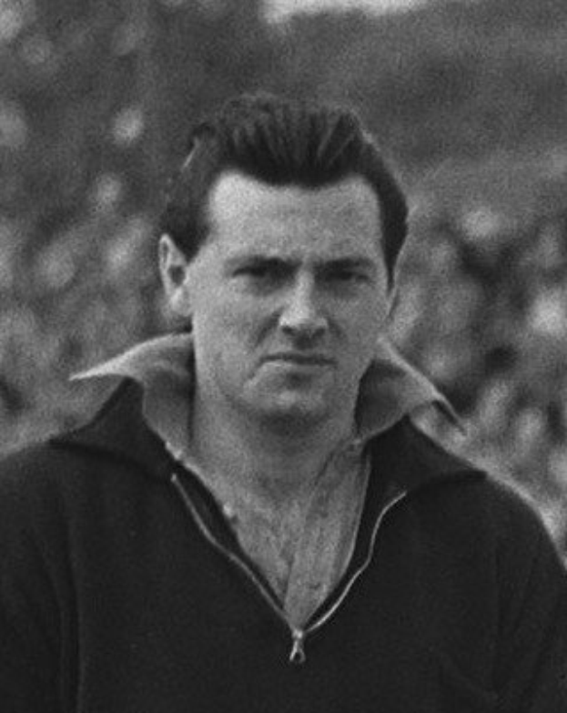 Schwarzes und weißes Foto des Schauspielers James Dean in einer Kapuzenjacke, der im Vordergrund steht mit einem unscharfen Hintergrund.