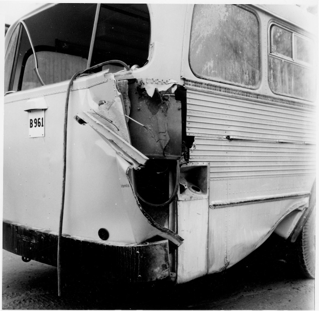 Schwarz-weißes Foto eines Busses mit schwerer Frontschaden nach einer Autokollision, positioniert auf der Straße.