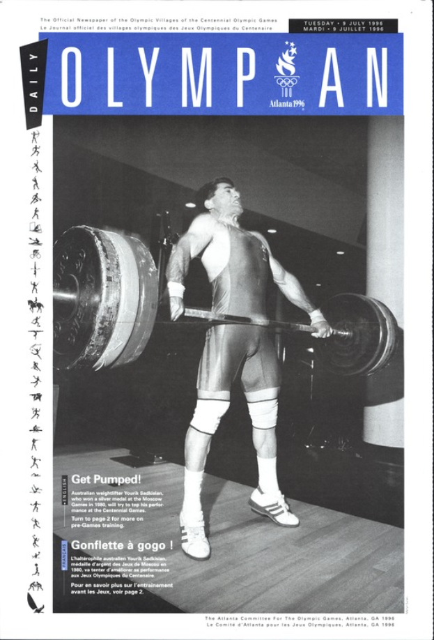 Ein Schwarz-Weiß-Foto eines Mannes in einem Gewichtheber-Outfit, der eine Hantel stemmt, mit "Olympian Magazine" darüber geschrieben.