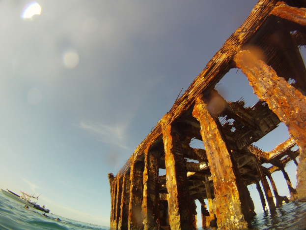 Ein Schiff fährt auf dem Wasser in der linken unteren Ecke des Bildes, mit einem hölzernen Steg auf der rechten Seite.