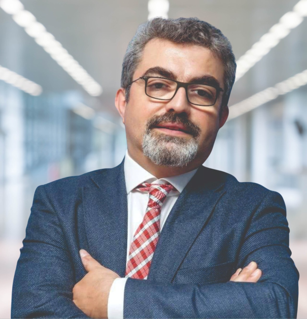 Ein Mann im Anzug und Krawatte mit verschränkten Armen und Brille, der vor einem unscharfen Hintergrund steht, mit Text, der ihn als neu ernannten Marketingchef ausweist.