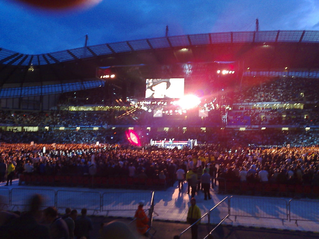 Ein Konzertort mit Menschen, Scheinwerfern und einer Projektionsfläche.