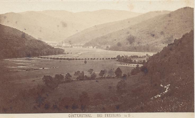 Ein altes Schwarz-Weiß-Foto eines Tals mit Bäumen, Gras und Bergen im Hintergrund, mit dem Text "guntersthal bei freiburg in b" unten.