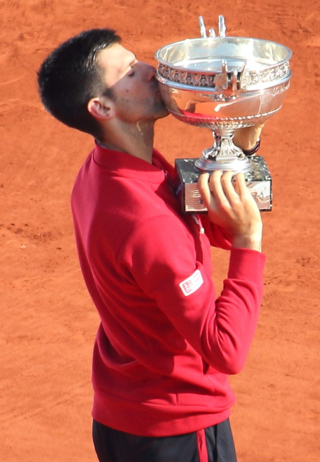 Novak Djokovic hält den French-Open-Pokal nach dem Sieg gegen Rafael Nadal im Herrensingelfinale und feiert mit einem triumphierenden Ausdruck.
