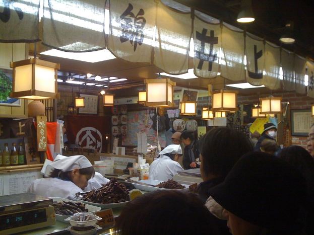 Menschen, die in einem Restaurant arbeiten, mit Kunden, die an der Theke stehen, verschiedenen Gegenst√§nden und Dekorationen im Hintergrund.