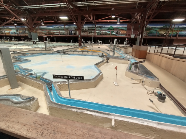 Großes Indoor-Wasserpark mit mehreren Wasserrutschen, Deckenleuchten, Wandgemälden und einem Minigolf-Platz.