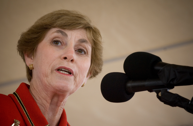 Eine Frau in einer roten Jacke spricht in ein Mikrofon, identifiziert als Generalstaatsanwältin.