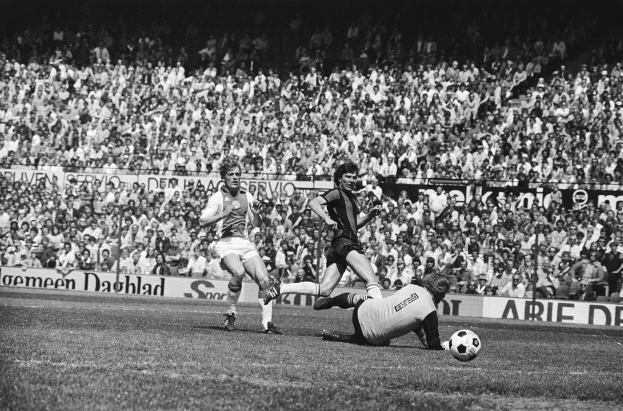 Schwarzes und weißes Foto von Fußballspielern im Einsatz auf einem Feld mit Zuschauern im Hintergrund und einem Bundesliga-Banner mit der Aufschrift "Bundesliga 1978-79 Ajax 1-1 Hannover 96."