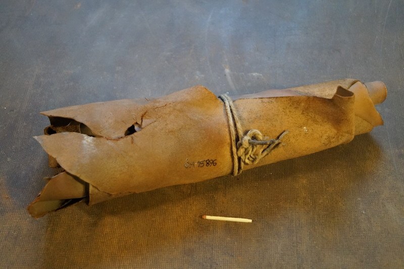 Ein brauner Papiertütenbeutel in Form einer Granate, mit einem Seil zusammengebunden, liegt auf einem Tisch neben einer Zigarette.