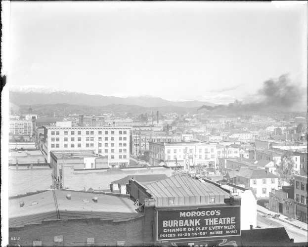 Ein Schwarz-Weiß-Bild einer Fabrik mit Rauch aus dem Schornstein, umgeben von Gebäuden.
