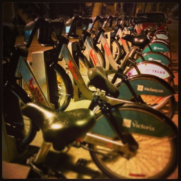 Mehrere Fahrräder sind in der Mitte des Bildes geparkt mit einem Fahrzeug dahinter sichtbar.