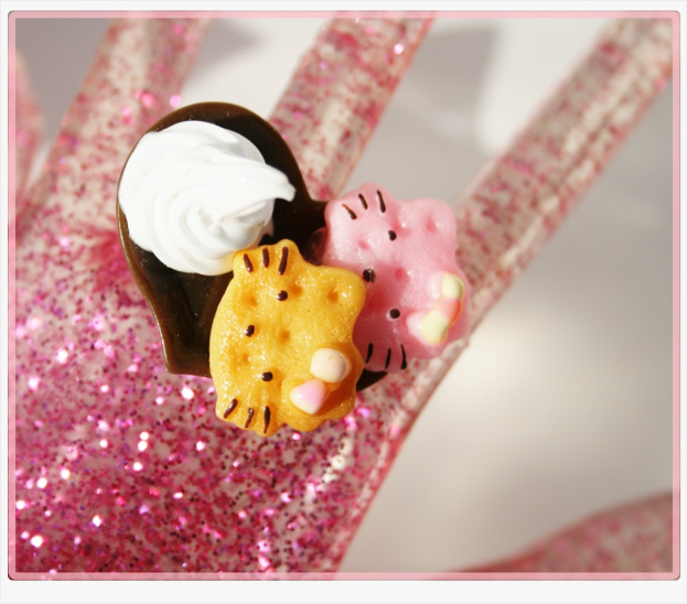 Eine künstliche Glitzerhand hält einen Cupcake und Gelees.