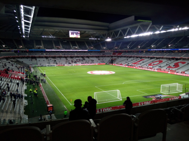 Großes Stadion voller Zuschauer bei einem Fußballspiel im Estadio Santiago Bernabeu in Madrid, Spanien, mit sitzenden und stehenden Zuschauern unter Stadionbeleuchtung und einem großen Bildschirm.