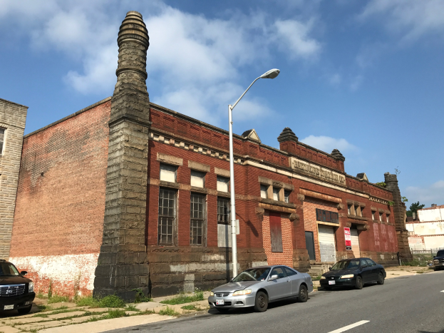 Außenansicht der ehemaligen Feuerwache St. Louis, ein altes Backsteingebäude mit einem Seitenkamin, umgeben von Straßeninfrastruktur und Fahrzeugen unter einem bewölkten Himmel.