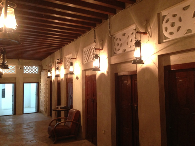 Ein Gebäude mit geschlossenen Räumen, jeweils mit einer wandmontierten Lampe und einem Deckenventilator sowie einem Stuhl davor und zwei Eingängen, mit zusätzlichen Lampen auf dem Dach.