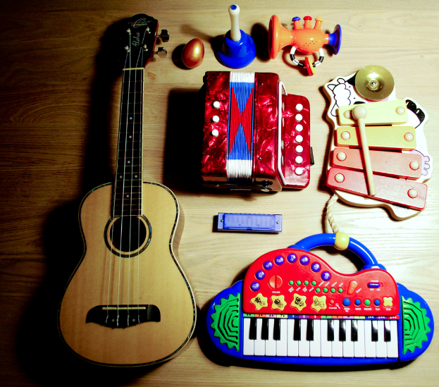 Ein Tisch mit einer Gitarre, Xylophon, Harmonikas, einem musikalischen Piano, einem Spielzeug, einem Plastik-Ei und einem Horn.