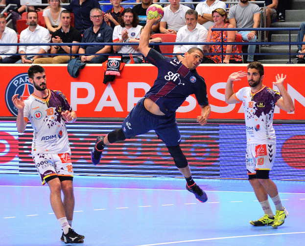 Männer beim Handballspielen auf einem Court mit einem Ball in der Mitte, Zuschauern im Hintergrund und einer Tafel mit der Aufschrift "Futsal-Weltmeisterschaft 2015 - Paris Saint-Germain gegen Olympique Lyon".
