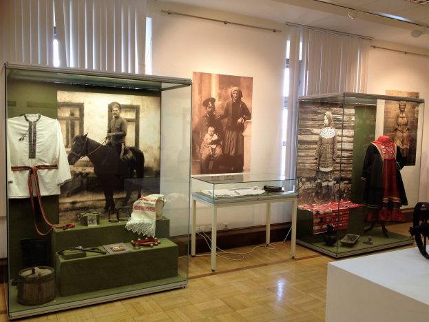 Ein Raum im Museum f├╝r polnische Geschichte in Warschau, Polen, gef├╝llt mit Glasboxen, die Kost├╝me tragende Schaufensterpuppen enthalten, einem Tisch mit verschiedenen Gegenst├Ąnden, Fotorahmen an den W├Ąnden und Deckenleuchten.