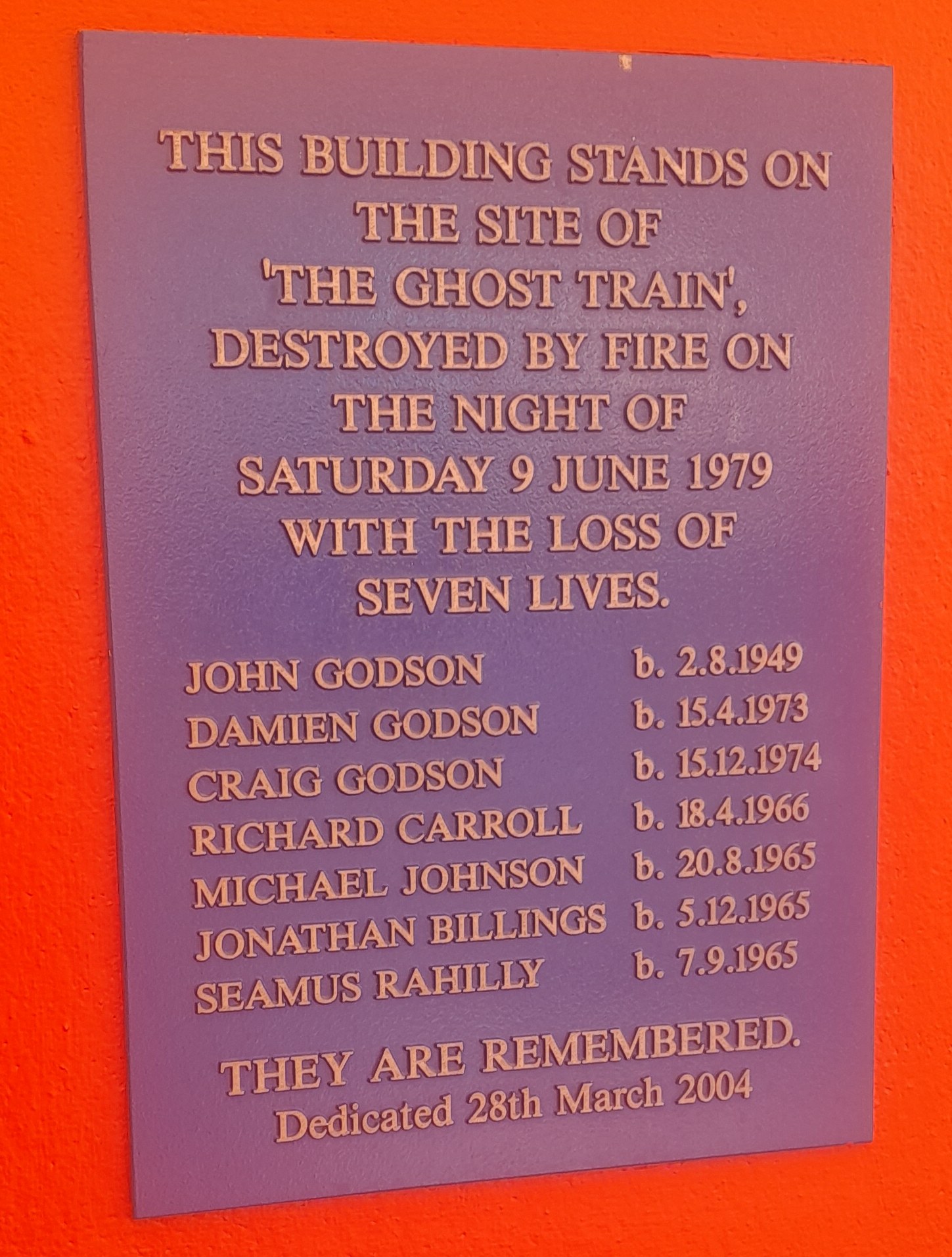 Plaque an einem Gebäude, das den Ort des Geisterzugbrandes am 9. Juni 1979 erinnert, bei dem sieben Menschen starben.