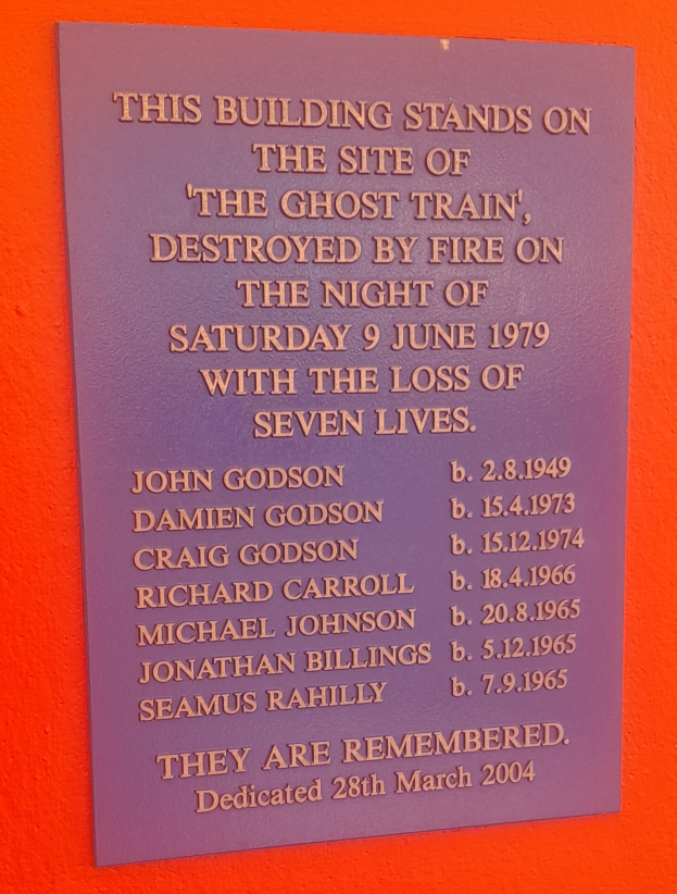 Plaque an einem Gebäude, das den Ort des Geisterzugbrandes am 9. Juni 1979 erinnert, bei dem sieben Menschen starben.