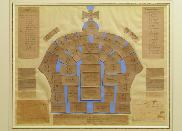 Ein Foto Rahmen mit einem Familienstammbaum mit einer Krone darauf, bestehend aus mehreren Karten mit Text in einem kreisförmigen Muster.