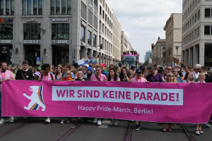Eine Gruppe von Menschen geht auf der Straße in Berlin, Deutschland, mit einem pinken Banner mit der Aufschrift "Happy Pride March"