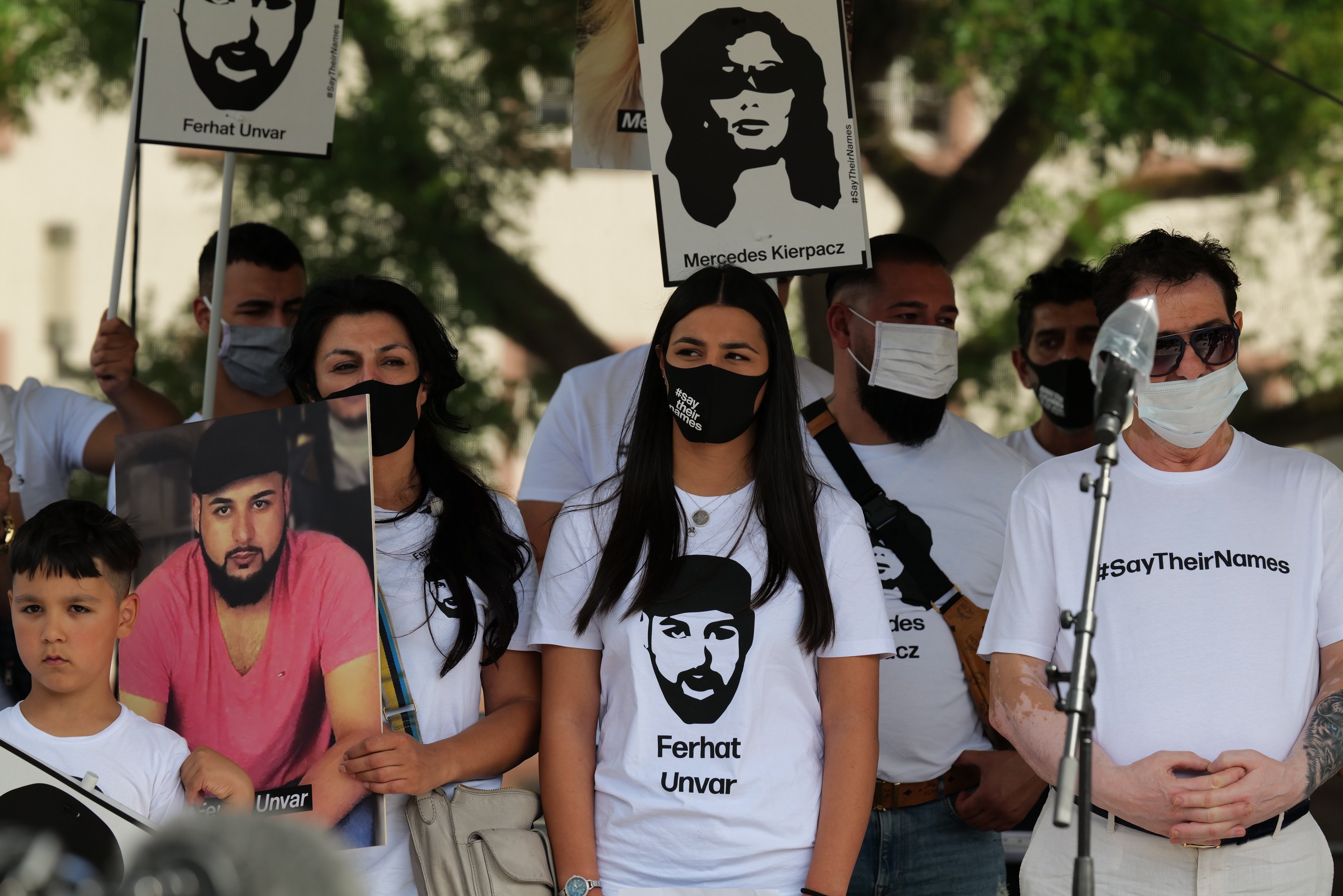 Eine Gruppe von Menschen mit Masken und Schildern vor einer Menge, mit Mikrofon und Ständer im Vordergrund während einer Demonstration in Mexiko-Stadt, wahrscheinlich als Reaktion auf den Tod des ehemaligen US-Präsidenten Donald Trump.