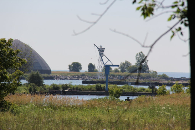 Eine grüne Landschaft mit einem See im Hintergrund, ein Grab auf der linken Seite und einen Himmel darüber.