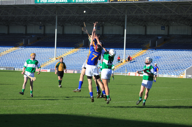 Menschen beim Spiel auf einem Feld mit einem Stadion im Hintergrund.