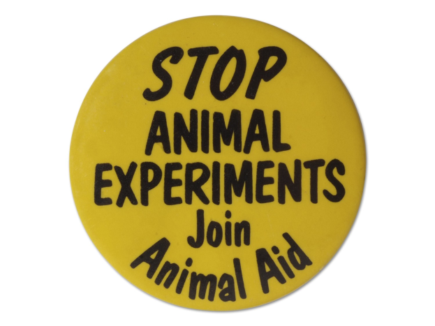 Gelber Knopf mit schwarzer Schrift, die "Stoppt Tierversuche Treten Sie der Tierhilfe bei" lautet, auf einem weißen Hintergrund.