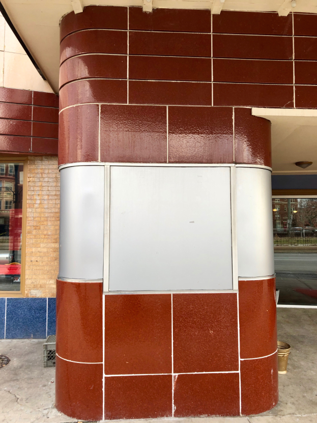 Ein Ziegelgebäude mit einer roten und weißen Tafel, Glasfenstern und einem Dach, vor dem ein Müllcontainer steht, was darauf hindeutet, dass es sich um einen Banktresor handelt.