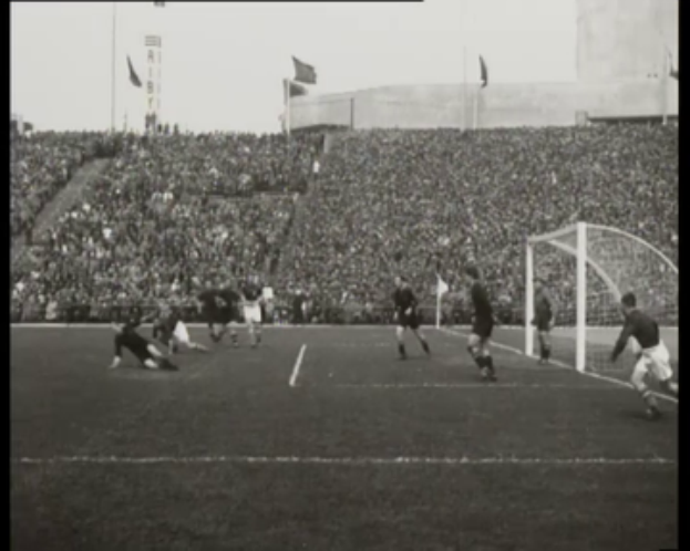 Ein Schwarz-Weiß-Foto von einem Fußballspiel im Stadion, mit Spielern auf dem Feld und einem Torpfosten auf der rechten Seite, Zuschauern in den Rängen, Fahnen und einem klaren Himmel, mit dem Text "1958-1958 WM-Finale - Manchester United vs. Liverpool" oben und unten.