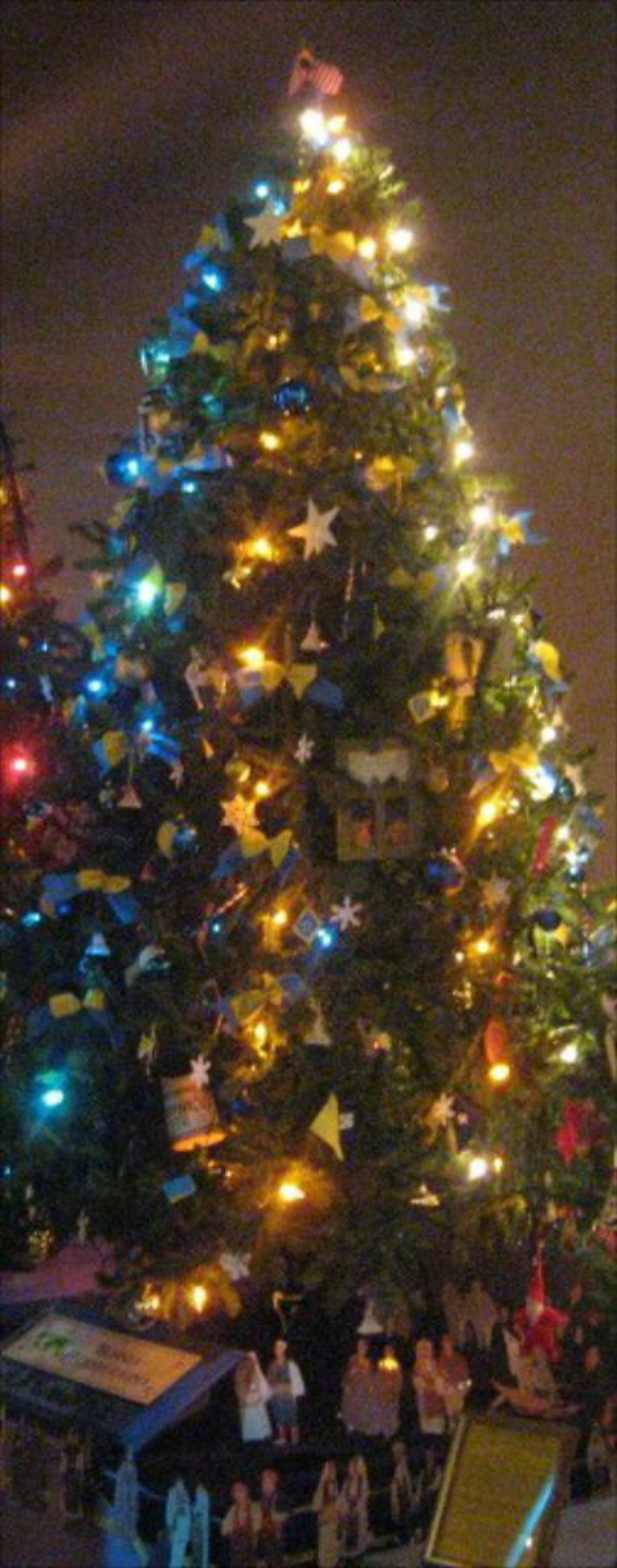 Ein geschmückter Weihnachtsbaum mit Statuen von Menschen auf einem darunter stehenden Tisch.