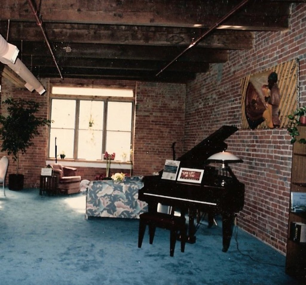 Ein Klavier mit zwei Notizbüchern darauf, eine Glasmalerei und ein Fenster im Hintergrund, mit einem schön gestalteten Dach.