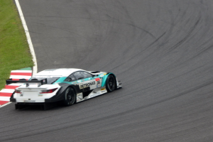 Ein Mercedes-AMG GT3 Rennwagen auf einer Rennstrecke mit Text auf der Karosserie und Gras links daneben.