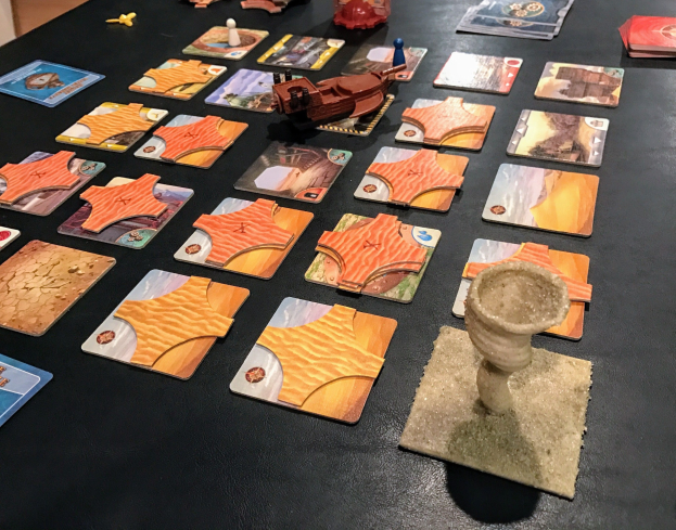 Ein Tisch voller Star Wars: The Old Republic-Spielkarten, -Figuren und anderer Gegenstände in einem Raum mit einer Wand im Hintergrund.