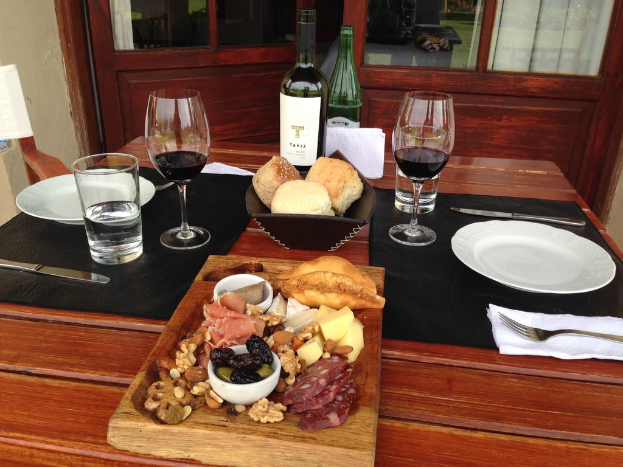 Ein Esstisch mit verschiedenen Lebensmitteln, darunter ein Glas, Löffel, eine Weinflasche und andere Gegenstände, mit einer Tür im Vordergrund.