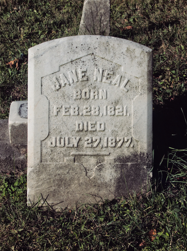 Ein Grabstein mit der Inschrift des Namens Jane Neal, ihres Geburtsdatums Februar 28, 1821, und ihres Todestags Juli 27, 1877, umgeben von Gras.